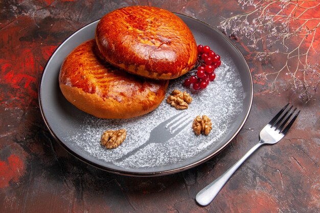 Vue avant de délicieuses tartes aux fruits rouges sur le bureau sombre pâtisserie gâteau tarte sucrée