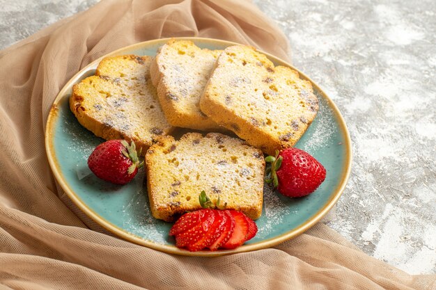 Vue avant de délicieuses tranches de gâteau avec des fraises fraîches sur la tarte aux fruits de surface légère