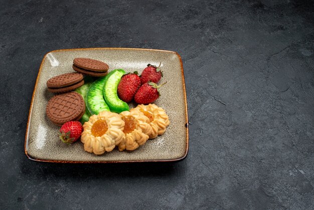 Vue avant de délicieux biscuits au chocolat et simples avec des fraises rouges fraîches sur mur gris foncé gâteau biscuit au sucre biscuit sucré