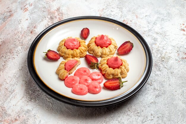 Vue avant de délicieux biscuits au sucre avec de la gelée de fraise sur un espace blanc