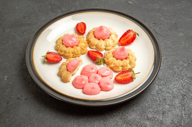 Vue avant de délicieux biscuits au sucre avec de la gelée de fraise sur l'espace gris