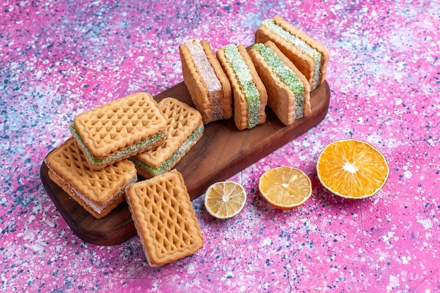 Vue avant de délicieux biscuits sandwich au citron sur plancher rose.