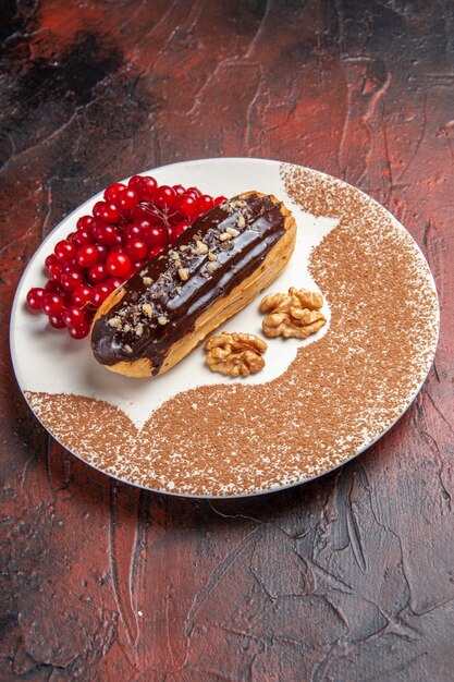 Vue avant de délicieux éclairs choco aux fruits rouges sur fond sombre