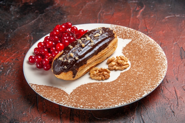 Vue avant de délicieux éclairs choco aux fruits rouges sur la tarte de table sombre gâteau dessert sucré