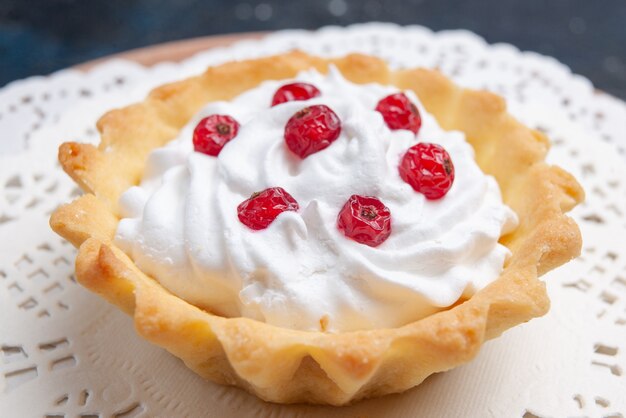 Vue avant de délicieux gâteau d avec de la crème et des fruits rouges sur la surface bleu foncé gâteau biscuit aux fruits sucré