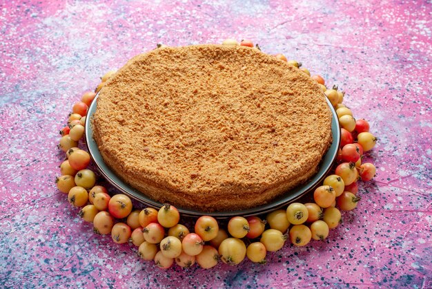 Vue avant de délicieux gâteau rond à l'intérieur de la plaque avec des cerises douces doublées sur rose vif bureau gâteau tarte biscuit sucre sucré