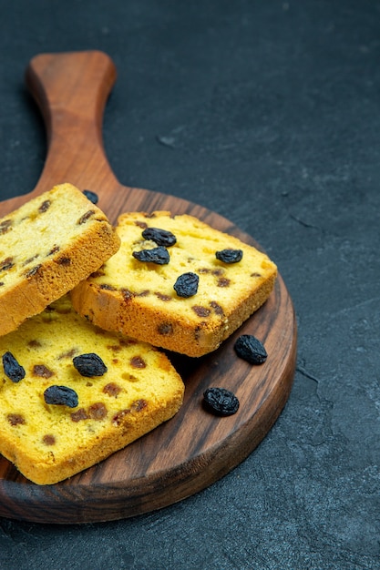 Vue avant de délicieux gâteaux aux raisins en tranches sur l'espace bleu foncé