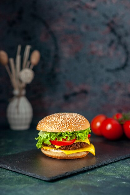 Vue avant de délicieux hamburger de viande aux tomates rouges sur fond sombre