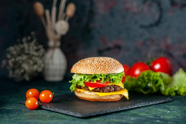 Vue avant de délicieux hamburger de viande aux tomates rouges sur fond sombre