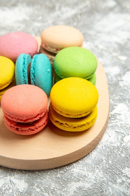 Vue avant de délicieux macarons français gâteaux colorés sur le bureau blanc gâteau tarte biscuit au sucre biscuit sucré