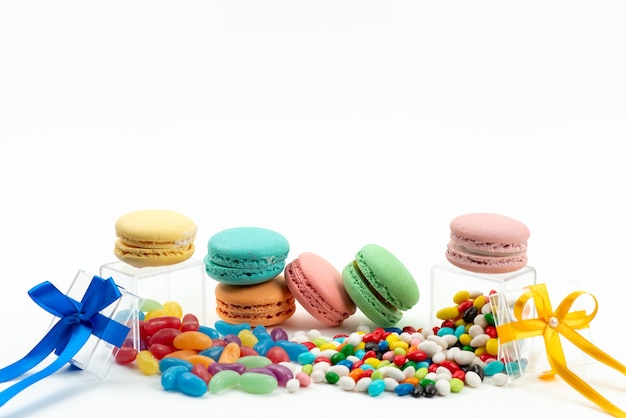 Une vue avant de délicieux macarons français ronde avec des bonbons colorés sur blanc, couleur biscuit gâteau