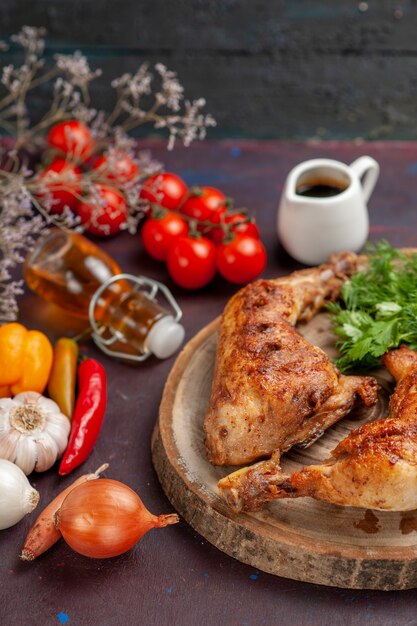 Vue avant de délicieux poulet frit avec des légumes frais et des verts sur un espace sombre