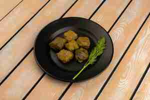 Photo gratuite vue avant dolma savoureux repas de viande à l'intérieur de la plaque noire sur le plancher en bois rustique