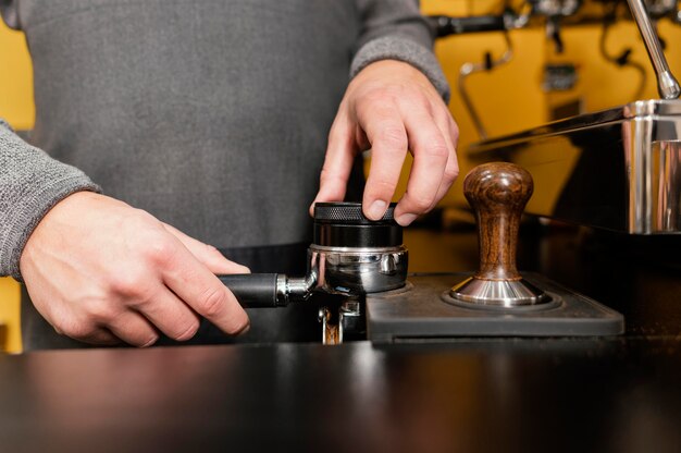 Vue avant du barista masculin à l'aide d'une tasse de machine à café professionnelle