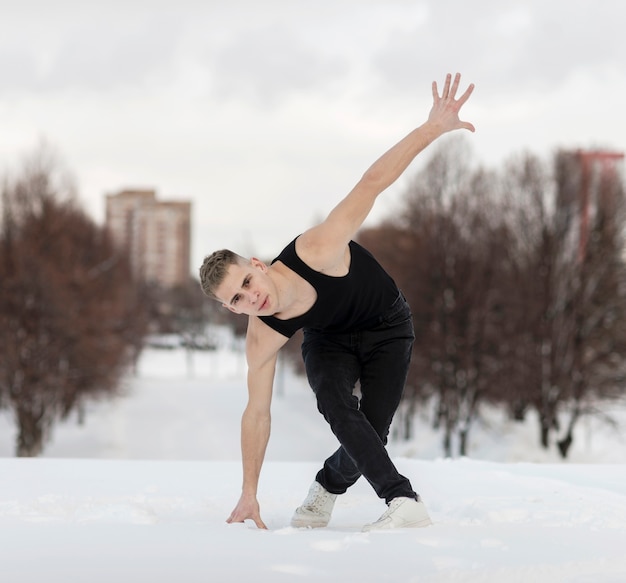 Vue avant du beau danseur masculin à l'extérieur avec de la neige