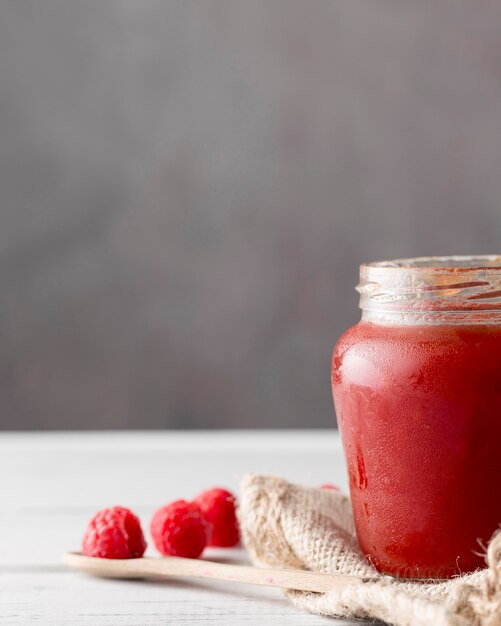 Vue avant du bocal en verre avec de la confiture de framboises et de l'espace de copie