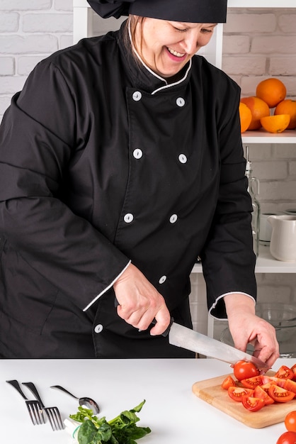 Vue avant du chef féminin, couper les tomates