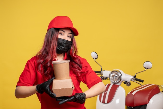 Vue Avant Du Courrier Féminin En Masque Avec Livraison De Nourriture Sur Mur Jaune