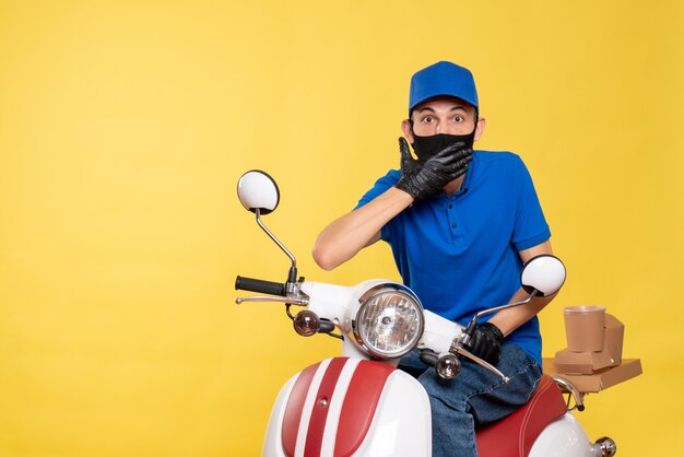 Vue avant du courrier masculin en uniforme bleu et masque sur vélo jaune covid- travail de service de virus de livraison pandémique