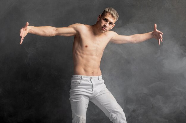 Vue avant du danseur masculin posant en jeans avec de la fumée