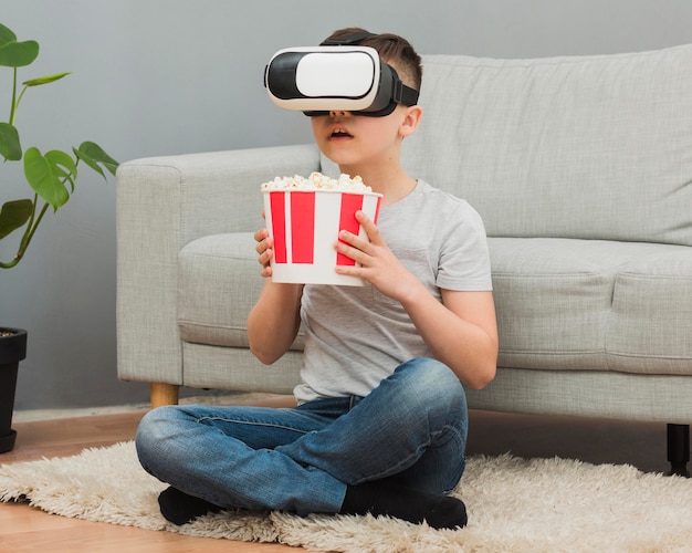 Vue Avant Du Garçon Avec Du Pop-corn En Regardant Un Film à L'aide D'un Casque De Réalité Virtuelle