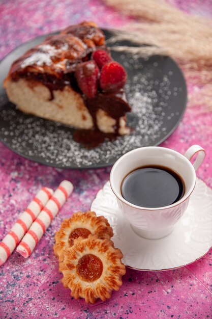 Vue avant du gâteau au chocolat aux fraises avec tasse de thé et biscuits sur le bureau rose biscuit sucré au sucre