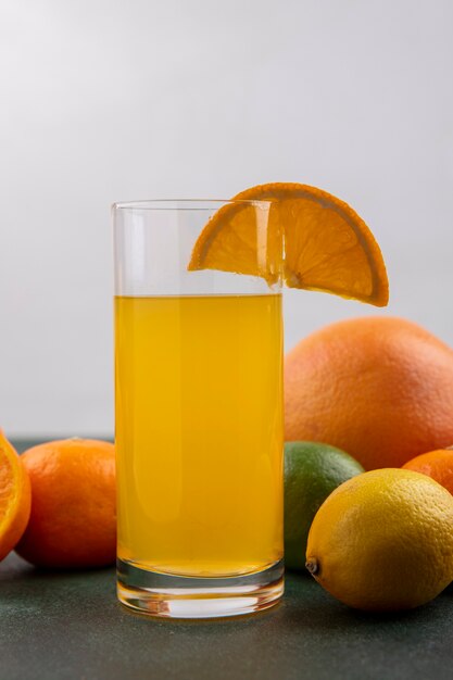 Vue avant du jus d'orange dans un verre avec des oranges citron vert et pamplemousse