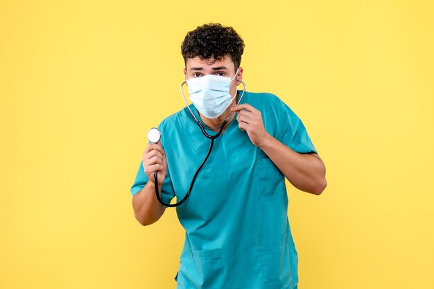 Vue avant du médecin le médecin en masque met le phonendoscope hors tension