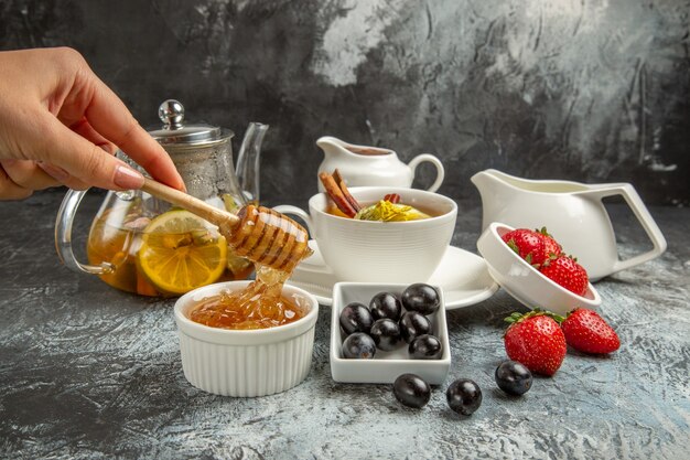 Vue avant du miel sucré avec du thé et des olives sur le petit-déjeuner du matin étage sombre