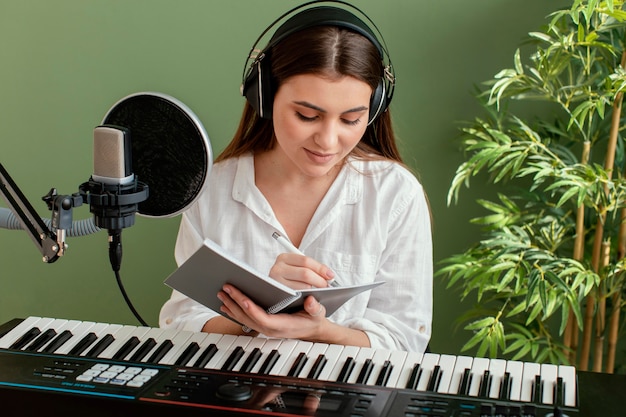 Vue avant du musicien féminin jouant du clavier de piano et écrivant des chansons pendant l'enregistrement