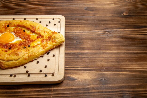 Vue avant du pain frais avec des œufs cuits sur la pâte de bureau rustique brun alimentaire petit-déjeuner pain aux œufs