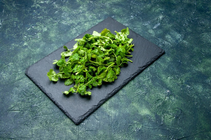 Photo gratuit vue avant du paquet de coriandre sur une planche à découper en bois sur fond de couleurs mélangées noir vert avec espace libre