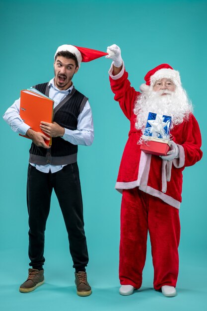 Vue avant du père Noël avec jeune homme et présente sur fond bleu neige vacances nouvel an vacances de Noël