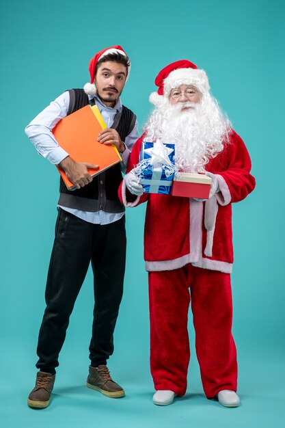 Vue avant du père Noël avec jeune homme et présente sur le fond bleu