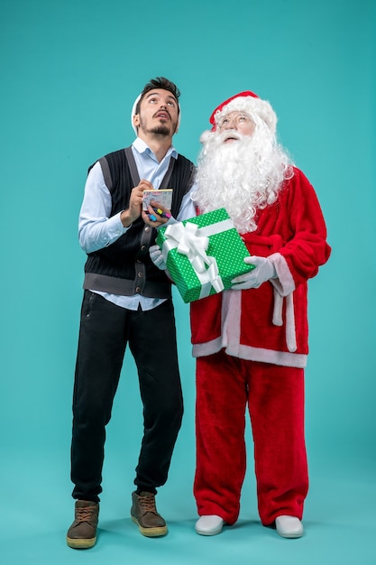 Vue avant du père Noël avec jeune homme qui prend des notes sur le fond bleu