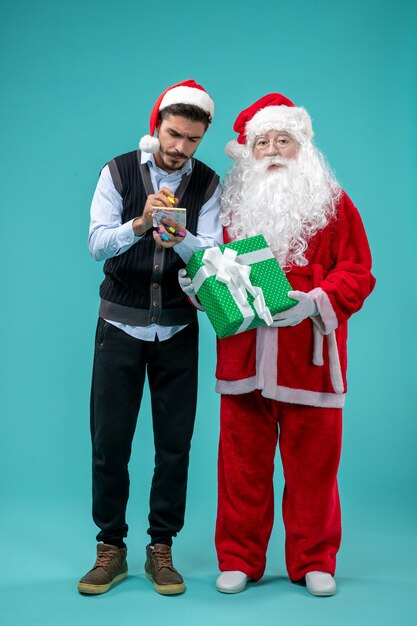 Vue avant du père Noël avec jeune homme qui prend des notes sur le fond bleu