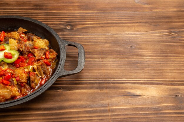 Vue avant du repas de légumes cuits à l'intérieur de la casserole sur la surface en bois brun