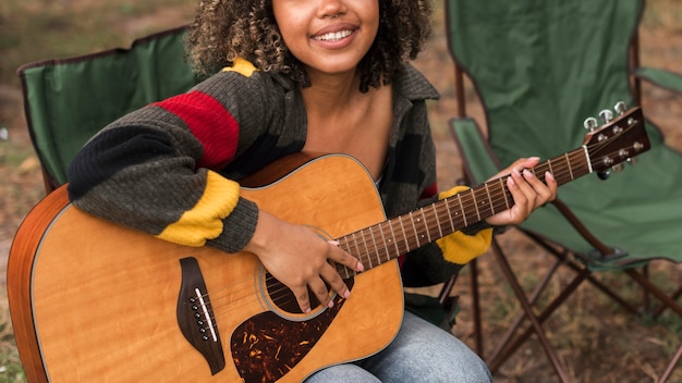 Vue avant du smiley femme jouant de la guitare en camping en plein air