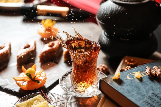 Vue avant du thé en verre armudu avec baklava et un livre sur la table