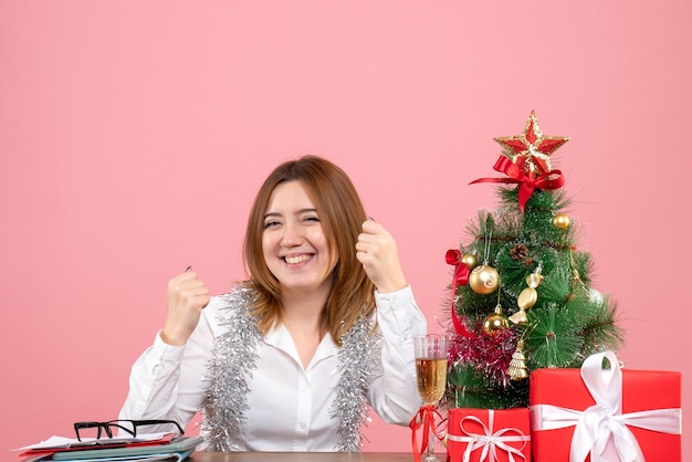 Vue avant du travailleur féminin assis derrière sa table se réjouissant joyeusement sur rose