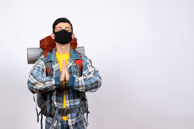 Vue avant du voyageur masculin avec sac à dos et masque joignant les mains