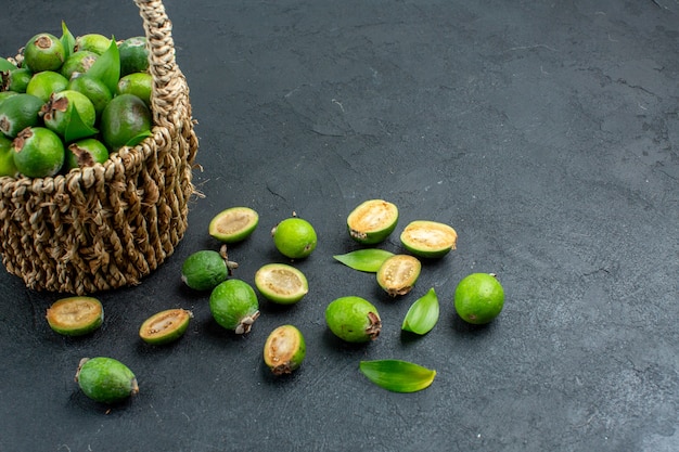 Vue avant des feijoas frais dans le panier sur l'espace libre de surface sombre