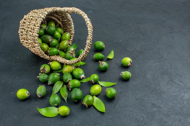 Photo gratuite vue avant de feijoas frais dans le panier sur une surface sombre avec espace de copie