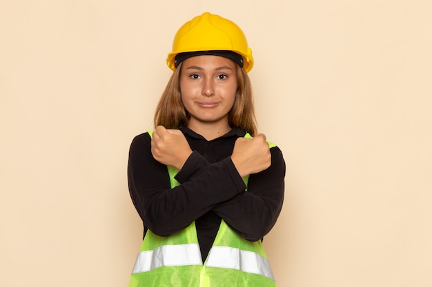 Photo gratuite vue avant femme constructeur en casque jaune souriant sur mur blanc