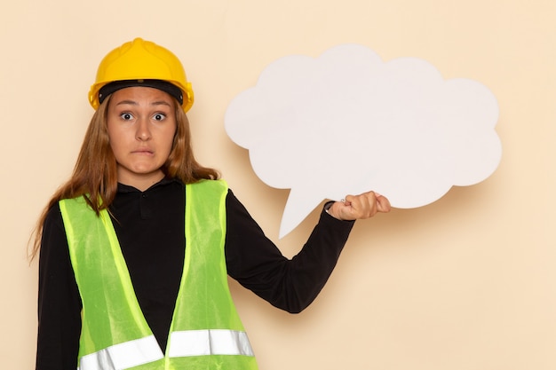 Vue avant femme constructeur en casque jaune tenant une pancarte blanche sur le plancher blanc femelle