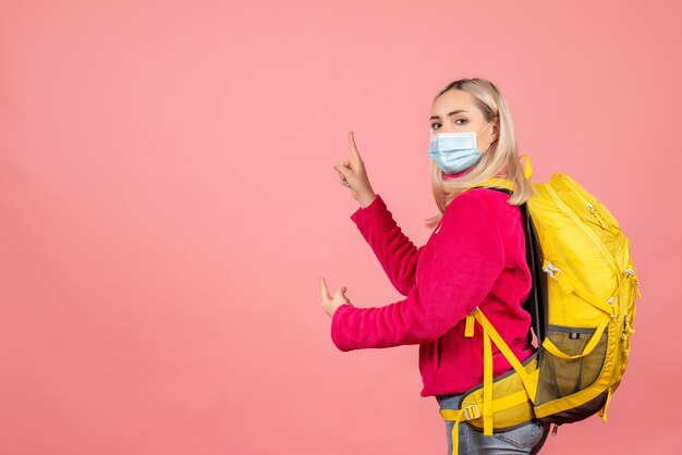 Vue avant femme voyageur avec sac à dos jaune portant un masque médical