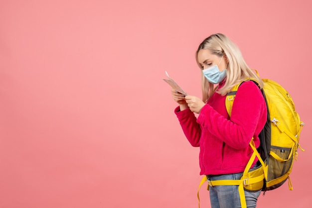 Vue avant femme voyageur avec sac à dos jaune portant un masque en regardant la carte