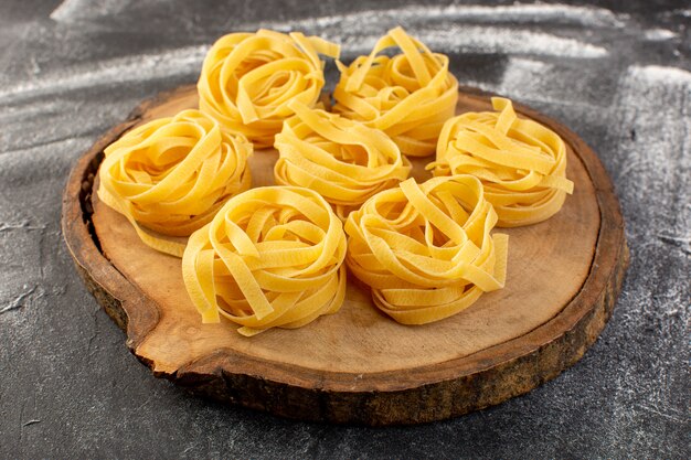 Vue avant en forme de pâtes italiennes en forme de fleur crue et jaune sur brun