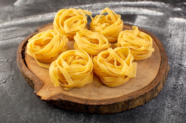 Vue avant en forme de pâtes italiennes en forme de fleur crue et jaune sur brun