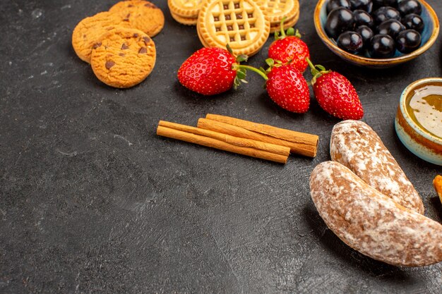 Vue avant des fraises fraîches avec des biscuits et des gâteaux sur une surface blanche bonbons fruits sucrés